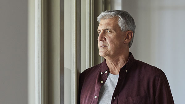 Thoughtful man looking through window.