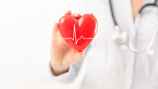 The doctor is holding and showing a red cartoon heart.