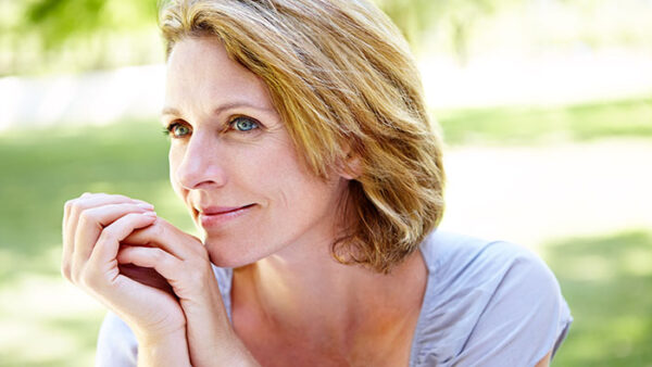 A mature woman relaxing on the grass and looking thoughtful