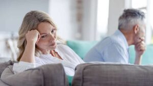 Mature couple fighting at home sitting on the sofa. They are both looking angry and frustrated.